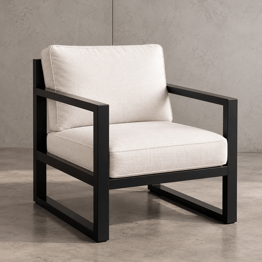 Fauteuil design PORTICO en fer noir mat avec coussins écrus, vue de trois quarts sur fond minéral.